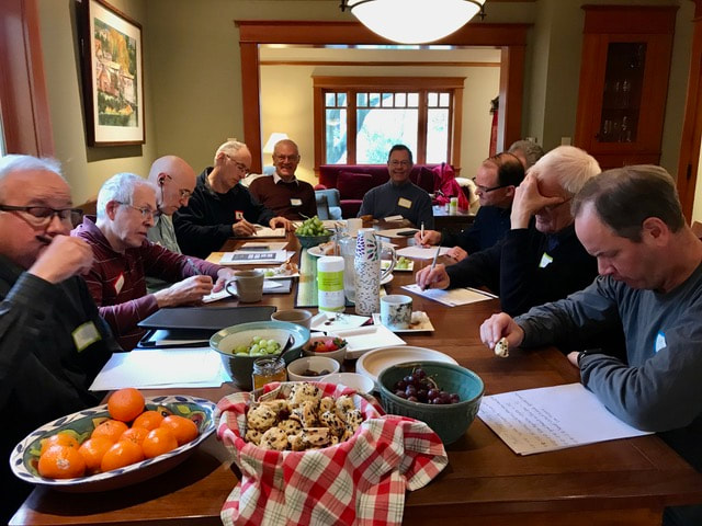 Picture of white men seated around a table at a meeting